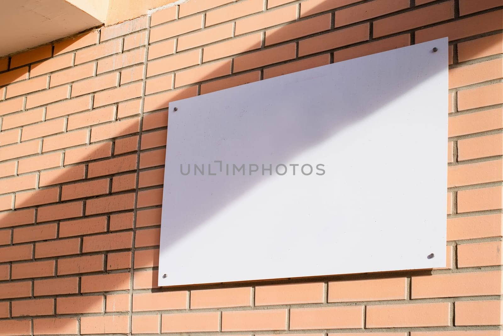 white rectangle logo on brick wall building exterior for mockup design by Desperada