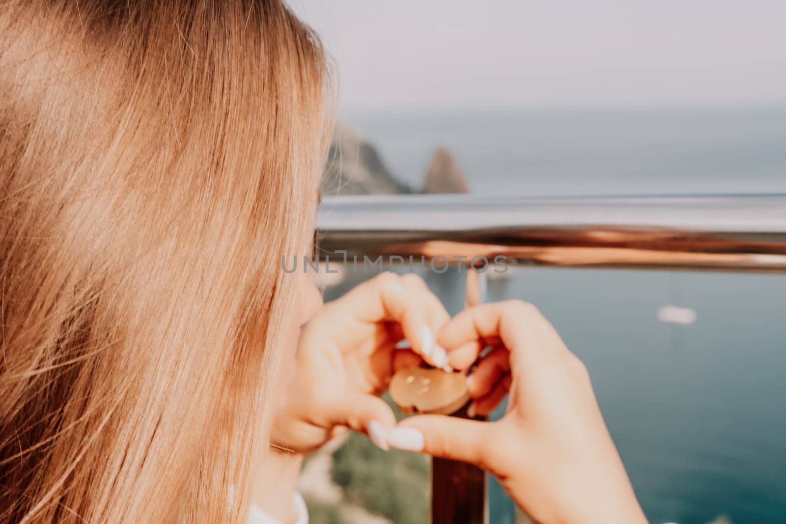 Hand, lock, heart, love, valentines day. Close up view of a woman holding a heart shaped lock that is locked onto a chain link fence.