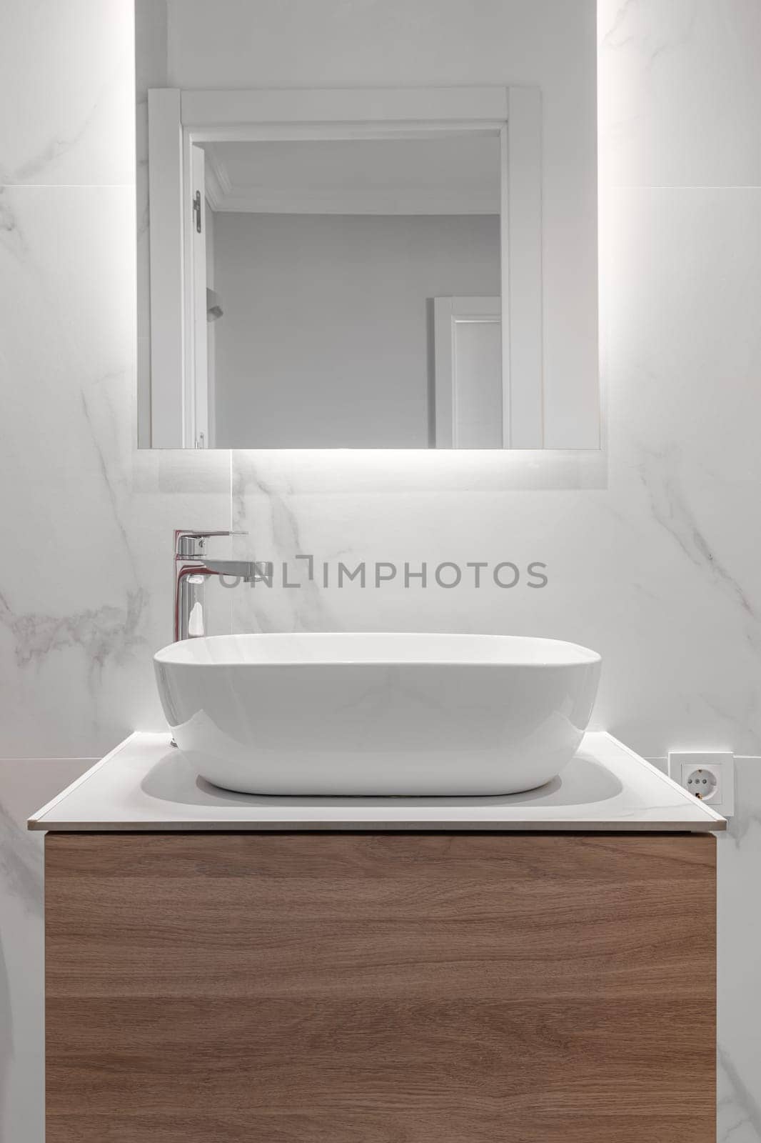 Close-up of an empty bathroom in white tones with a sink with a cabinet and a mirror in a new apartment. The concept of new plumbing and stylish design by apavlin