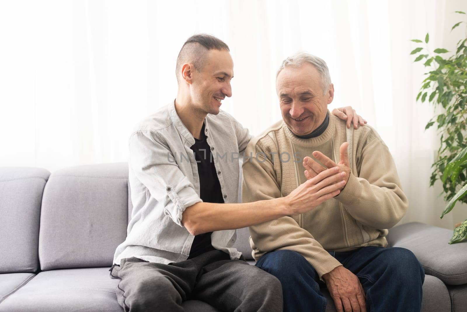 Help needed. Pleasant senior man sitting on the sofa.