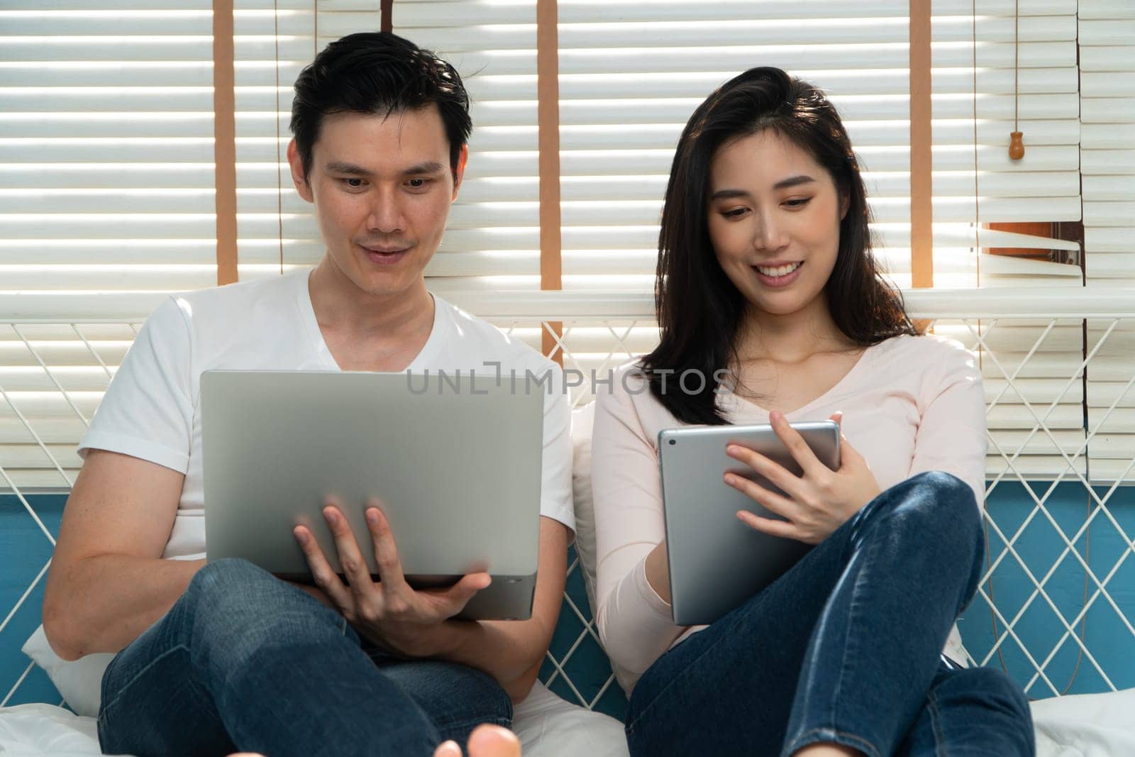 Happy young couple looking a tablet together for finding travel locations and book travel online for Honeymoon. Concept of Technology for convenience, Happiness after marriage by PattyPhoto