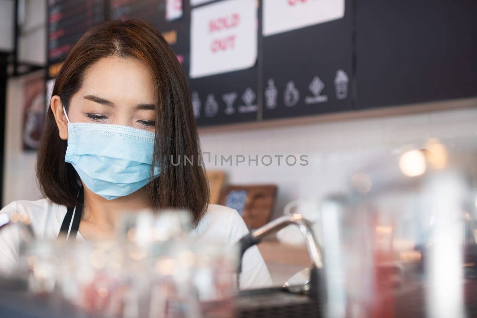 Asian barista women wearing face masks to prevent contagious diseases and serve customers in the coffee shop. The concept of prevention from COVID 19 by PattyPhoto