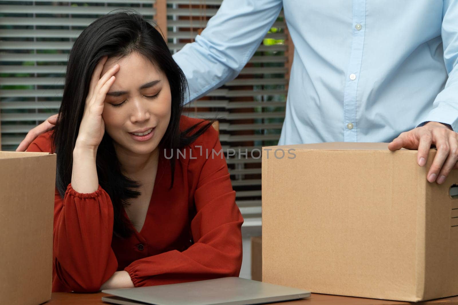 Sad Asian woman Packing belongings in a cardboard box and crying on the desk in the office After being layoff and unemployed. Concept of impact on the economic downturn And management of the failure by PattyPhoto