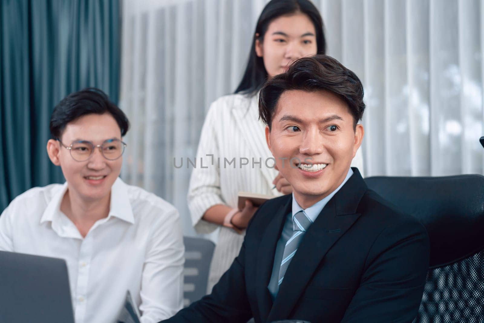 Portrait of focus young successful confident male manager, executive wearing business wear in harmony office arm crossed with blurred meeting background of colleagues, office worker.