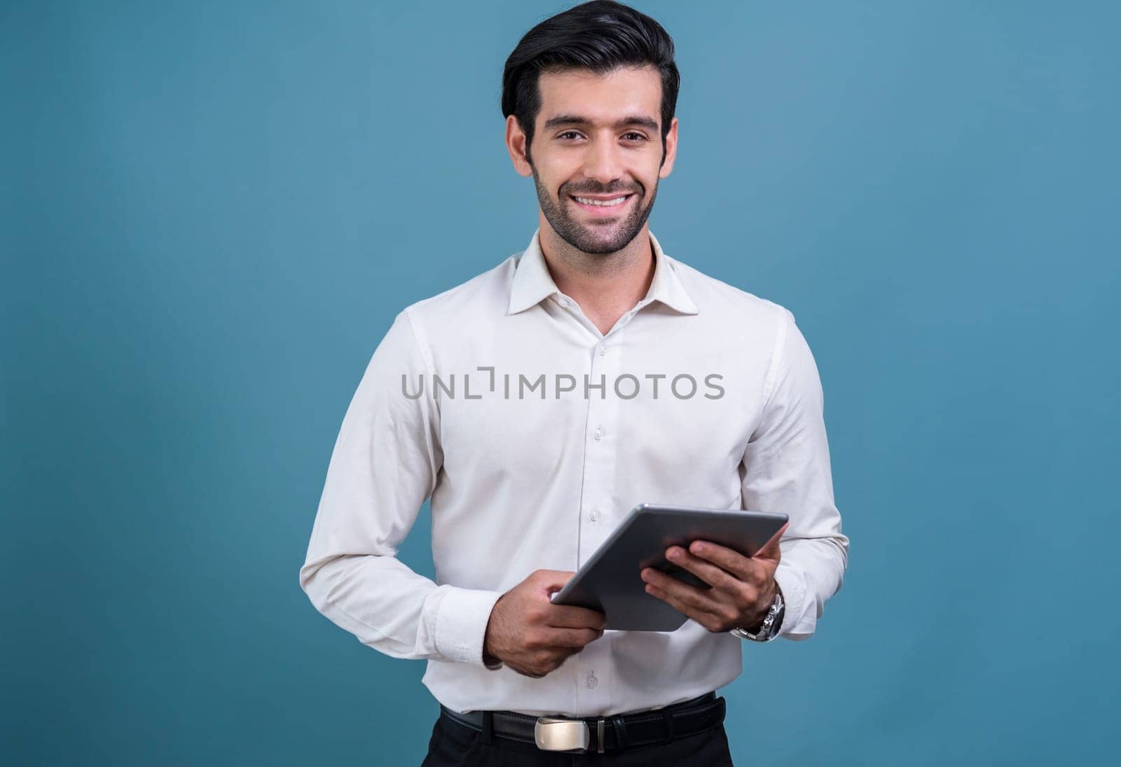 Confident businessman in formal suit holding tablet with surprise look for promotion or advertising. Facial expression and gestures indicate excitement and amazement on an isolated background. Fervent