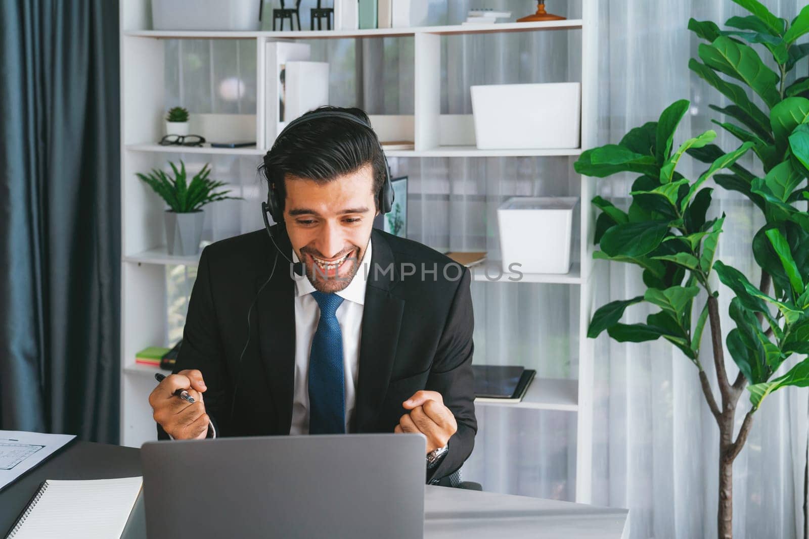 Male call center operator or telesales representative siting at his office desk wearing headset and in conversation with client providing customer service support or making persuasive sale. fervent