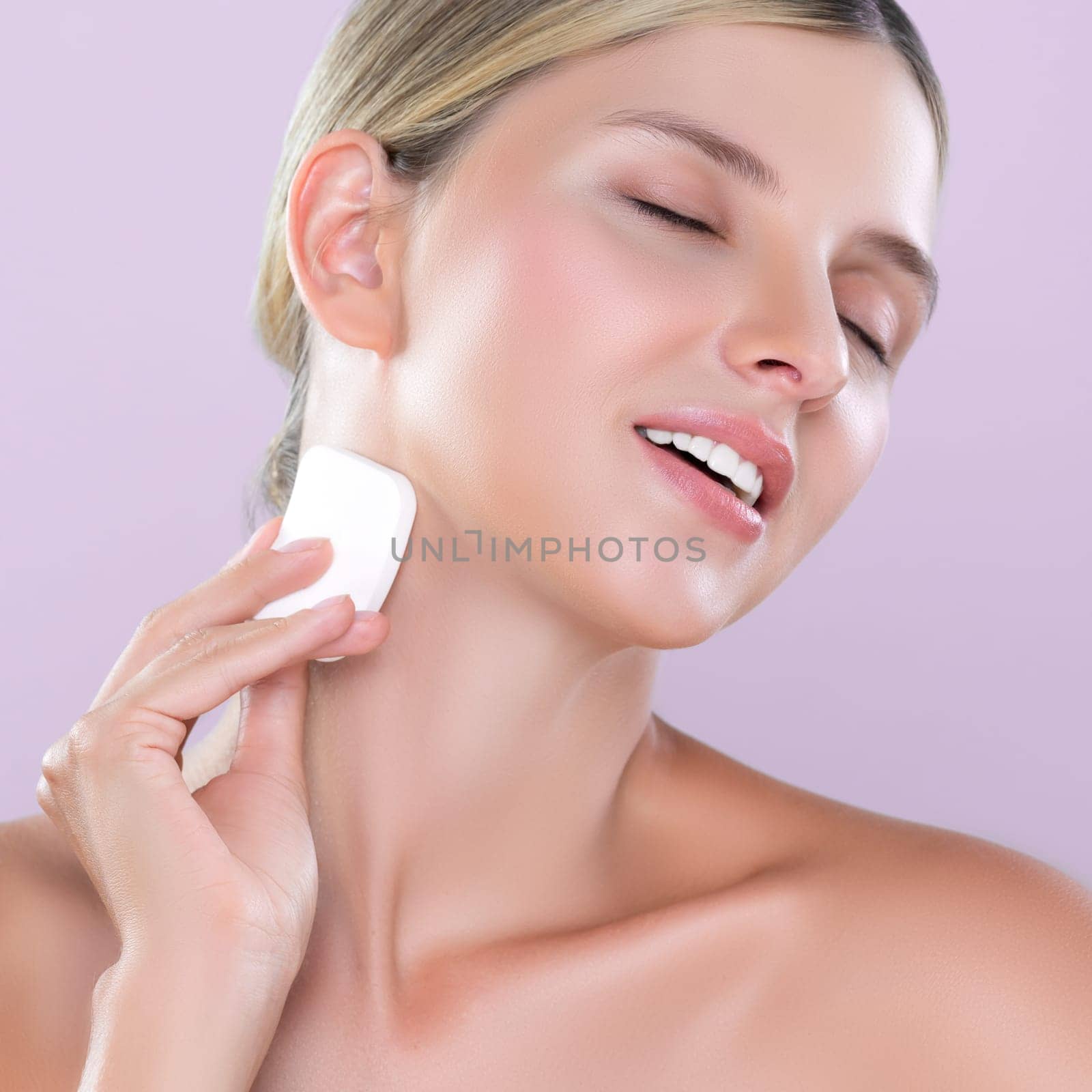 Closeup alluring beautiful female model applying powder puff for facial makeup concept. Portrait of flawless perfect cosmetic skin woman put powder foundation on her face in pink isolated background.