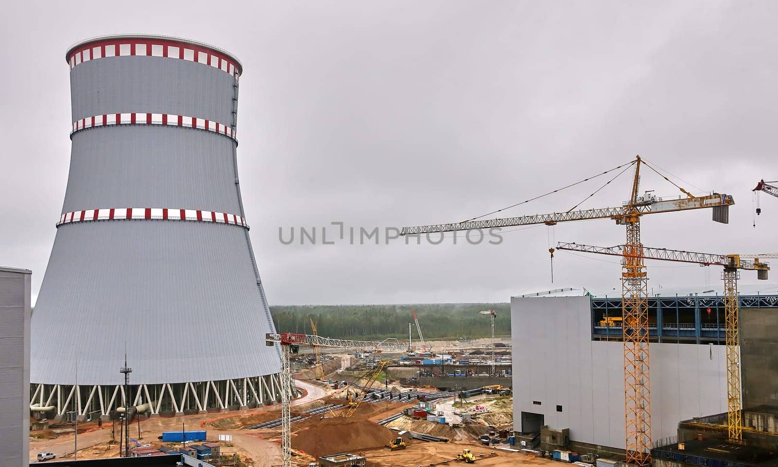 Construction of a nuclear power plant. Tower cranes on the background of the cooling tower.