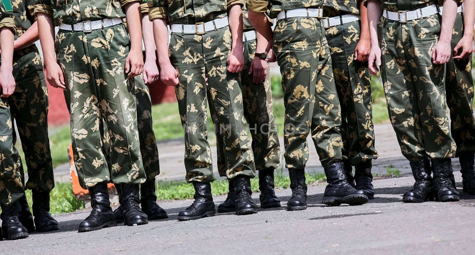 Russian military detachment of border guards stands on the street. Hands and boots close-up.