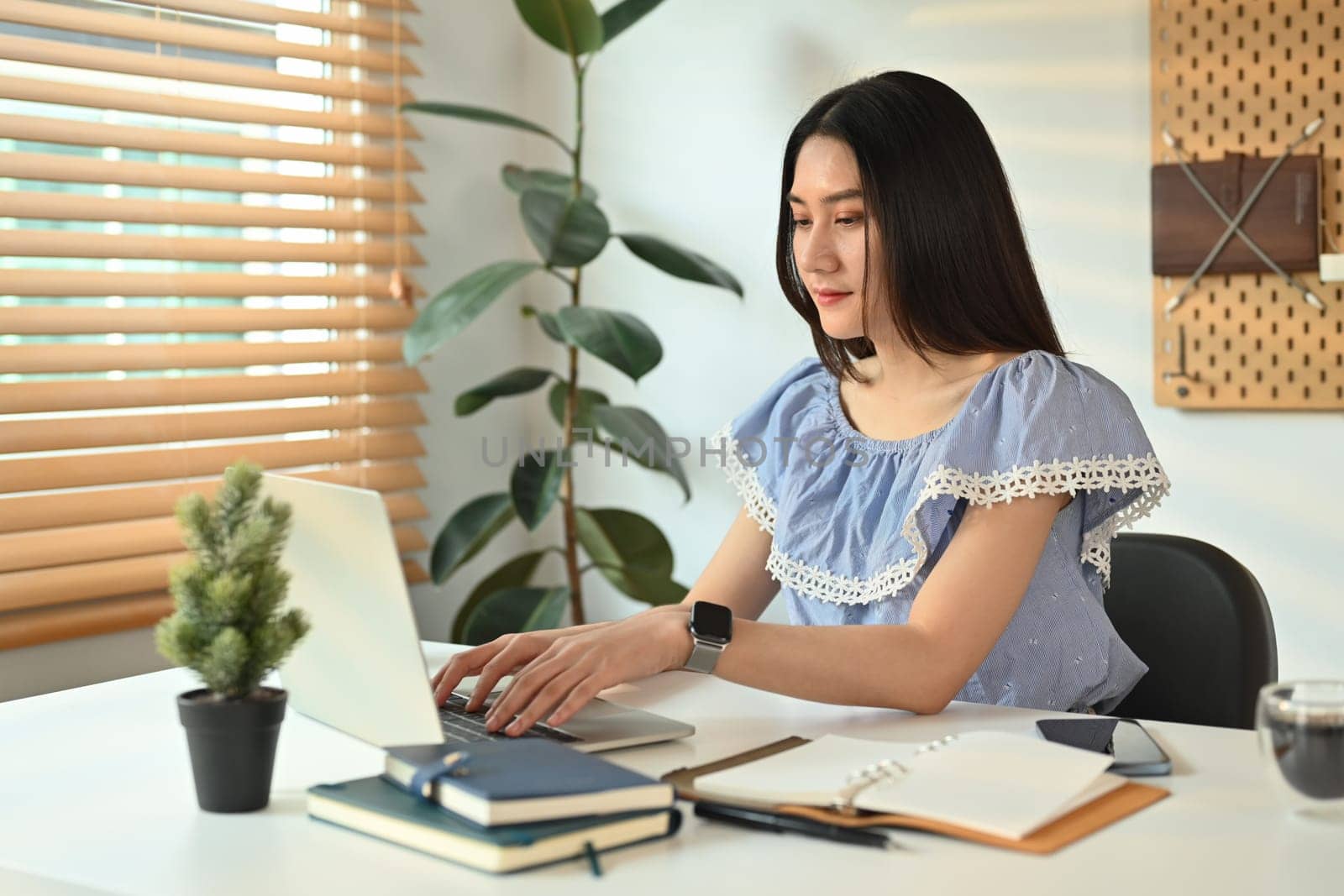 Young female entrepreneur chatting with client online on laptop computer, working on online marketing at home office.