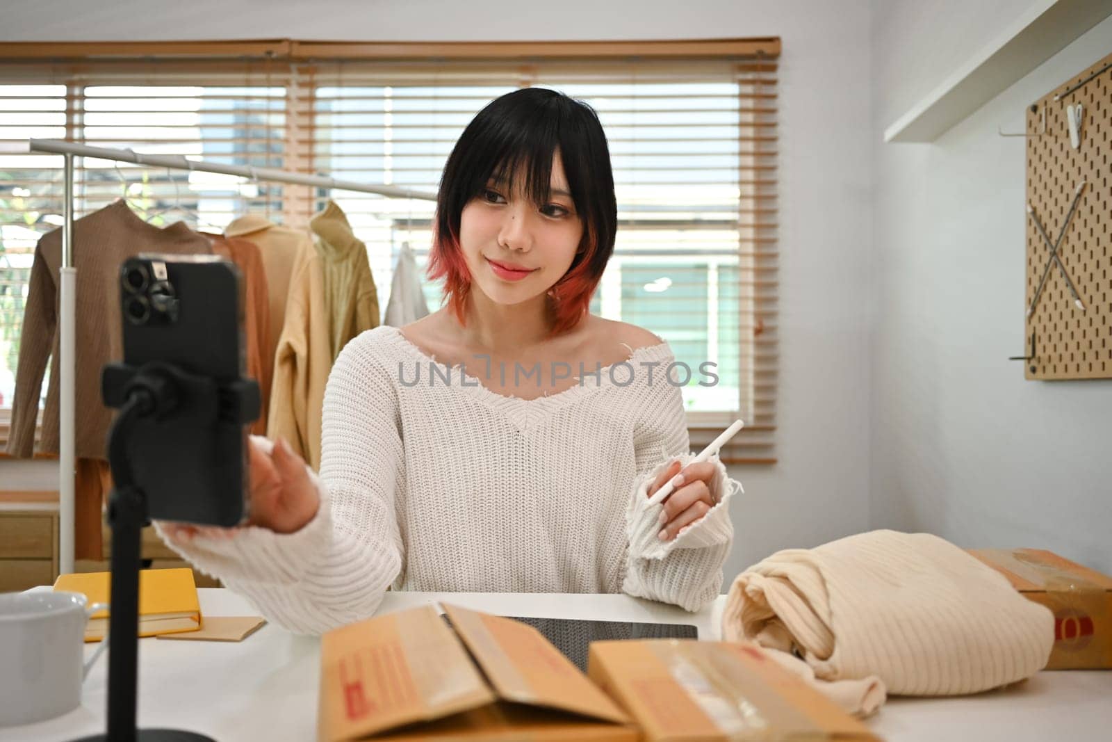 Young asian female small business owner in casual clothes and checking customer address or orders in an online store by prathanchorruangsak