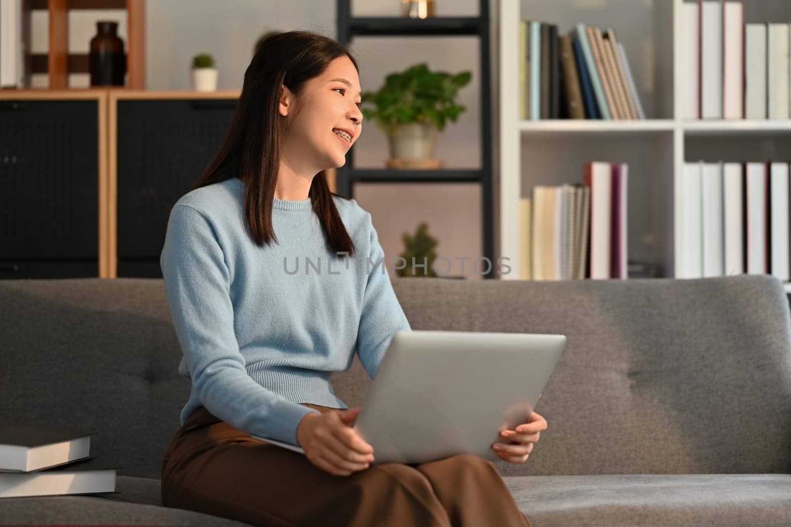 Nice asian woman using laptop computer on couch and smiling moment. High quality photo
