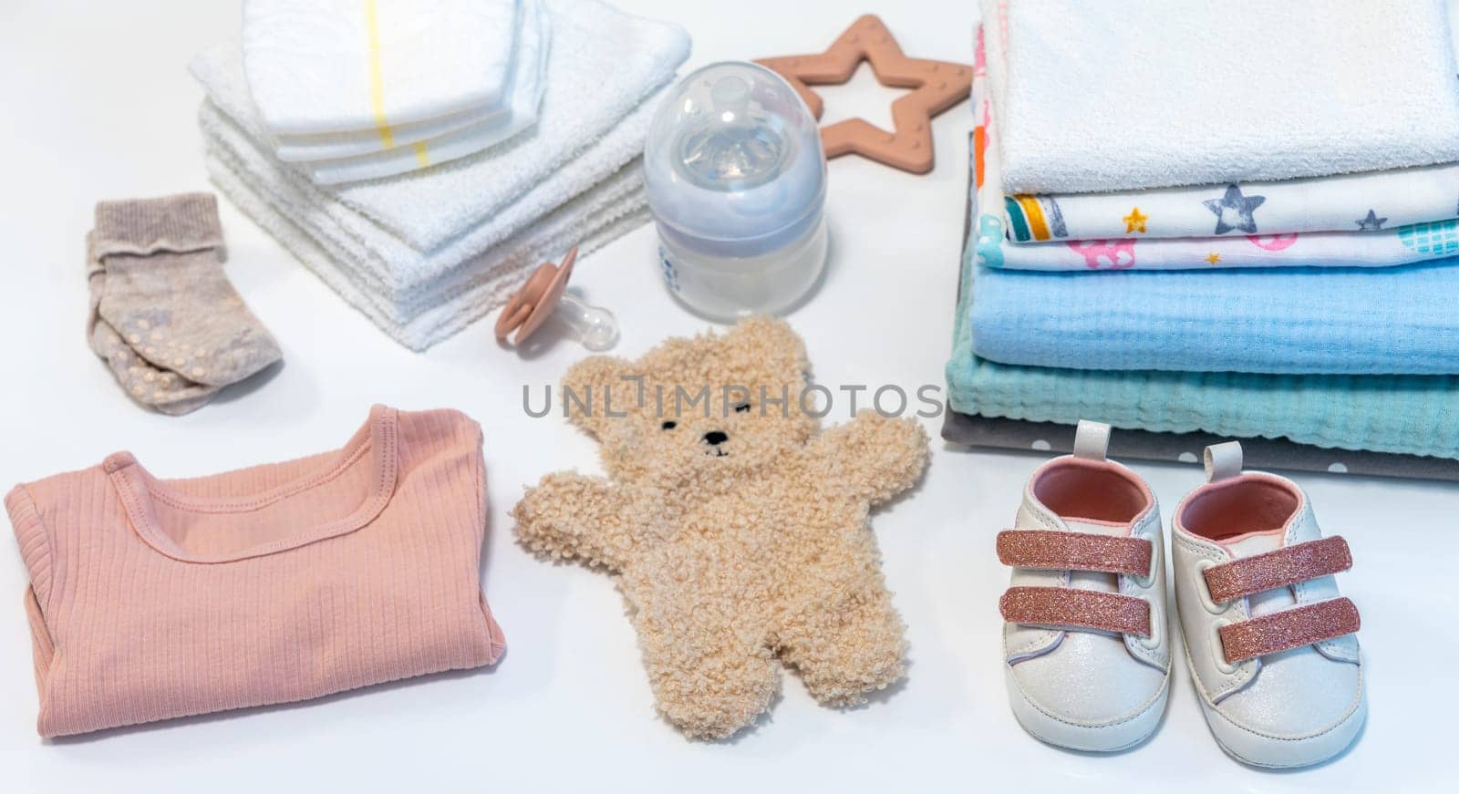 Baby girl clothes and accessories on a white table. Concept of newborn baby