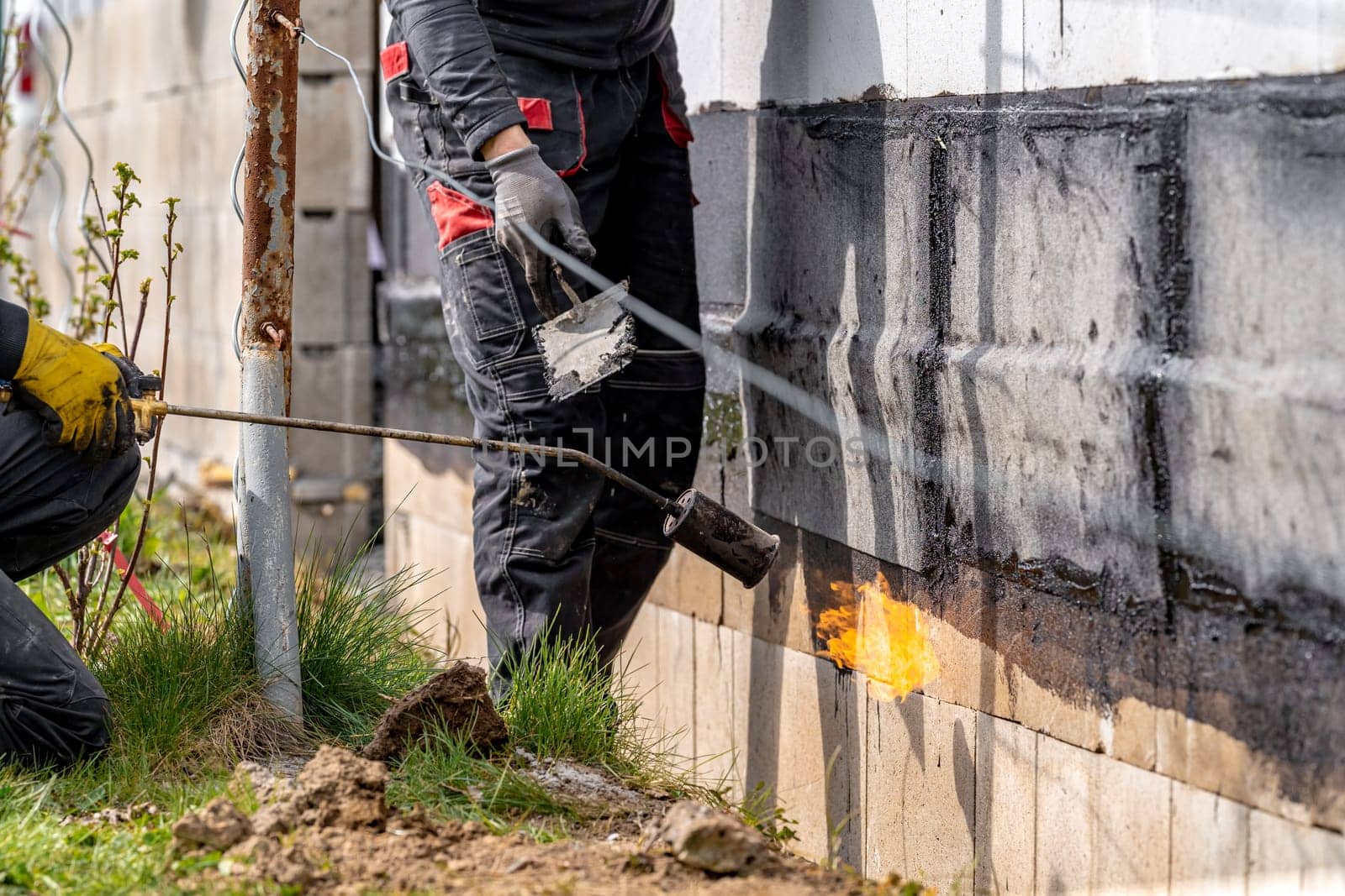 installation of protective waterproofing on the foundation and walls of the building. warmed by an open fire by Edophoto