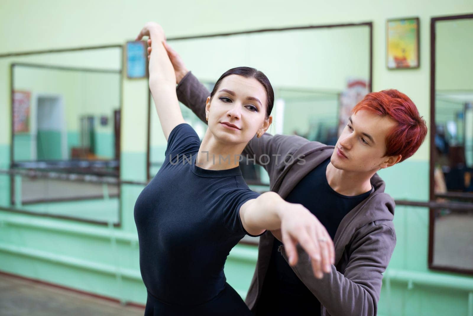 Male dance tutor helps ballerina to learn new moves and perform them correctly