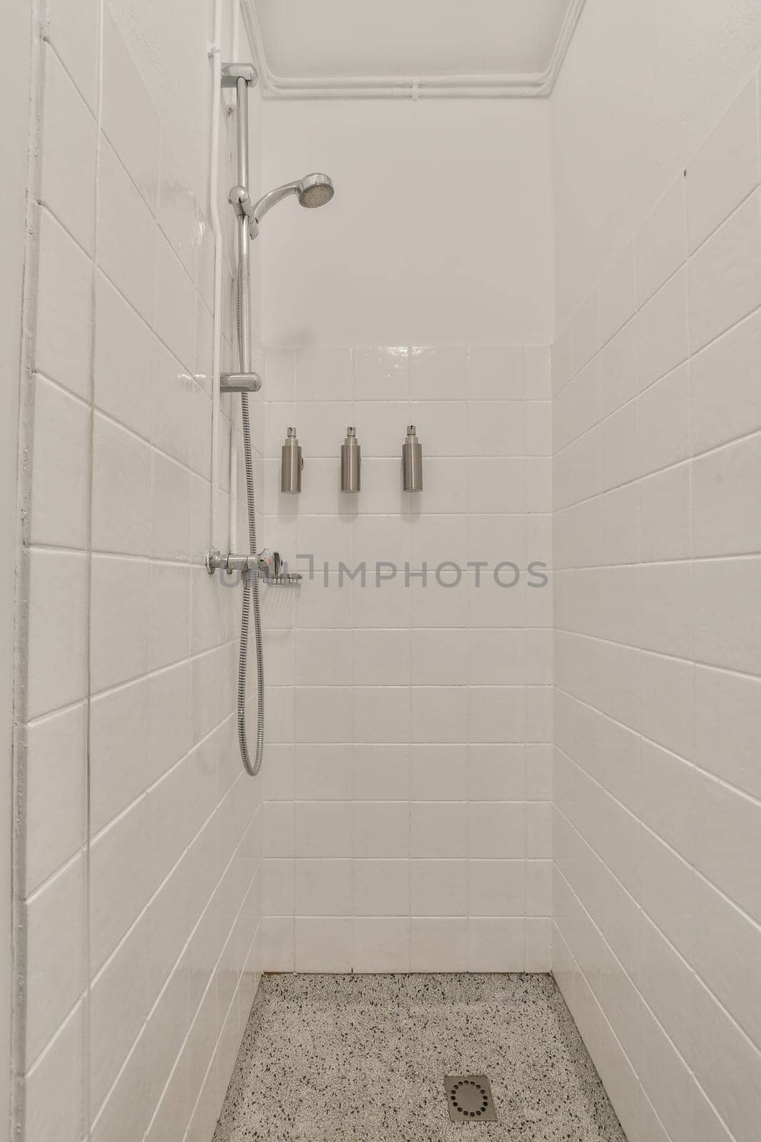 a walk in shower with white tiles on the walls and floor, it appears to be used as a bathtub