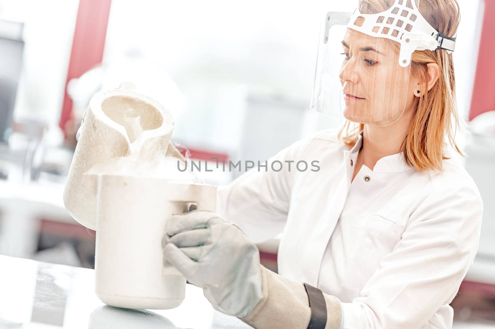 research with liquid nitrogen in the laboratory is carried out by a young female scientist with a protective glass face mask by Edophoto