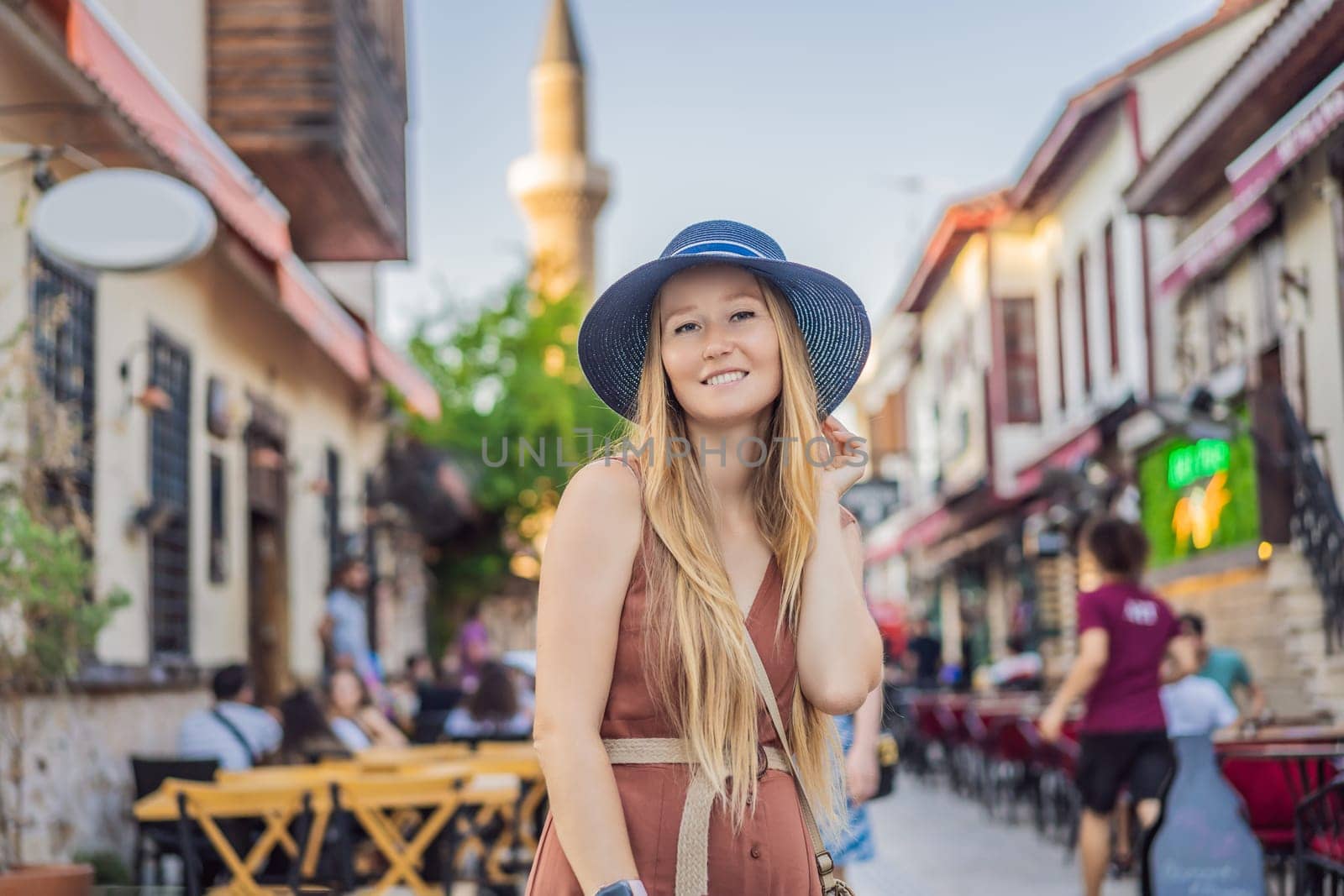 Happy woman tourist on background of old street of Antalya. female tourist traveler discover interesting places and popular attractions and walks in the old city Kalechi of Antalya, Turkey. Turkiye.