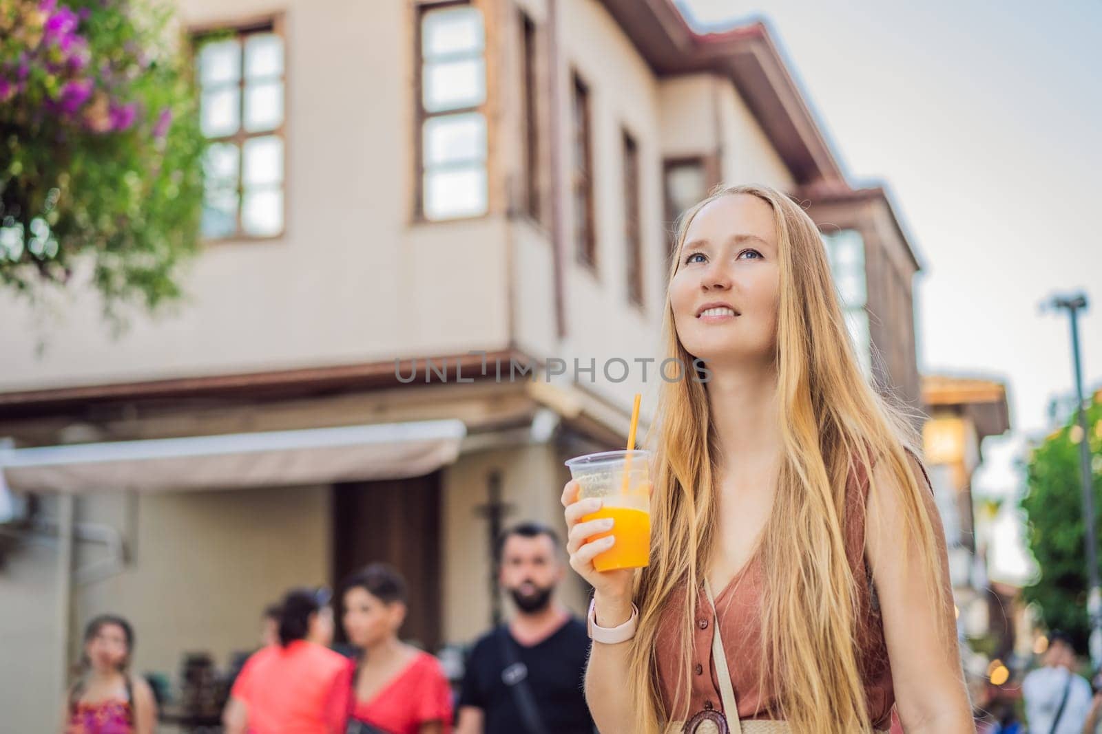 Happy woman tourist with fresh juice on background of old street of Antalya. female tourist traveler discover interesting places and popular attractions and walks in the old city Kalechi of Antalya, Turkey. Turkiye.