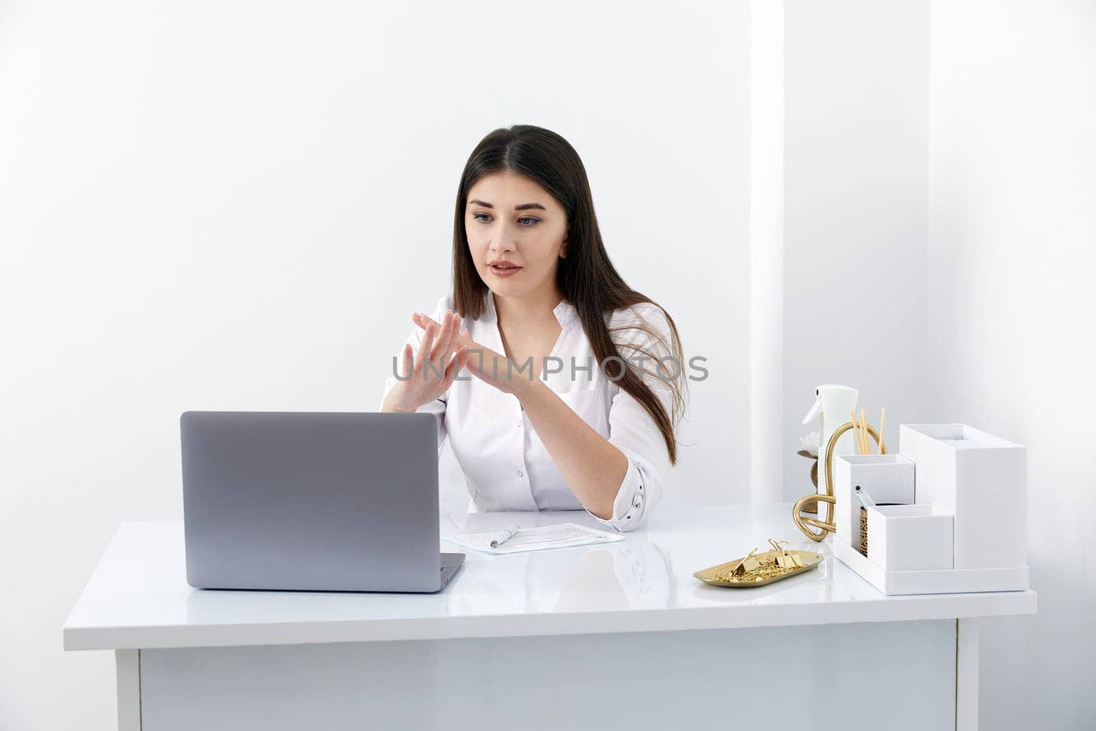 Portrait of female doctor talking to online patient on laptop screen sitting at clinic office desk giving online consultation for domestic health treatment. Telemedicine remote medical appointment