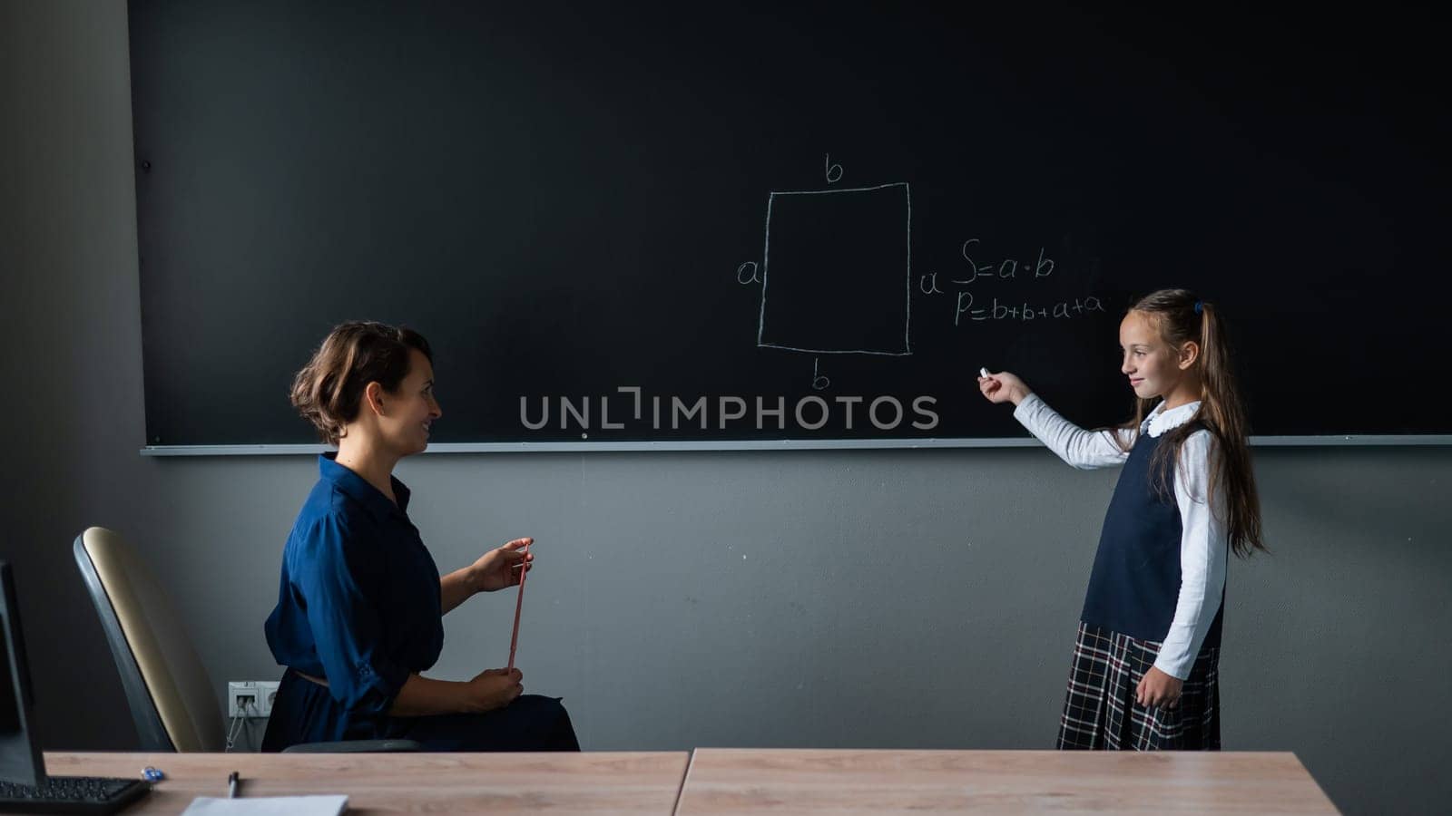 Caucasian little girl answers the question of the female teacher at the blackboard. by mrwed54