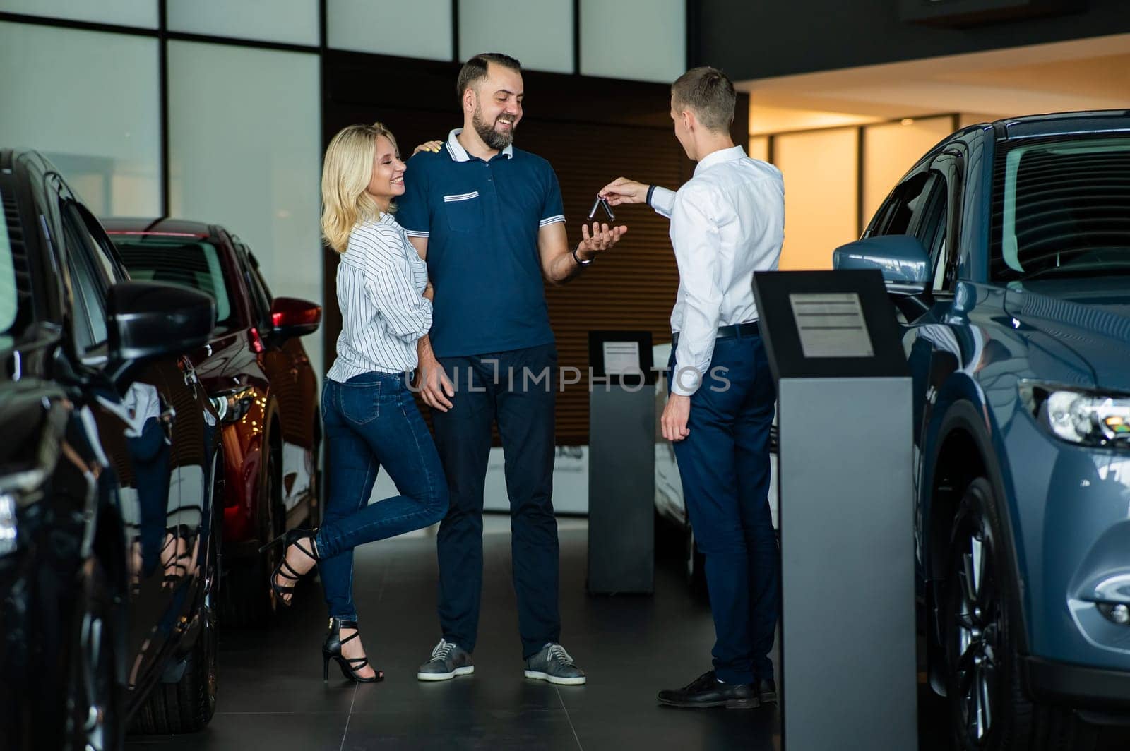 The seller hands over the car keys to the buyers. The couple bought a new car