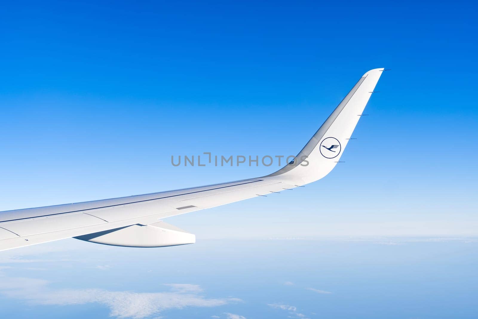 20.05.2022 - Tallinn, Estonia. Airplain wing with Luftansa logo view thrue window in the sky. Clouds and sky as seen through porthole of an aircraft with airplane's wing