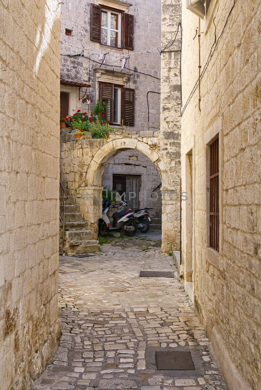 Narrow street with stone houses. Old houses and old narrow alley in Trogir, Croatia, Europe. Streets in old town.