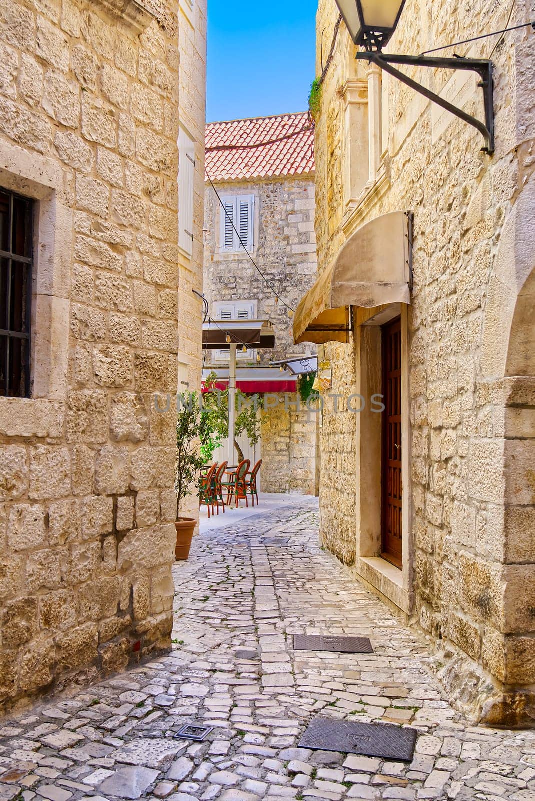 Narrow street with stone houses. Old houses and old narrow alley in Trogir, Croatia, Europe by PhotoTime