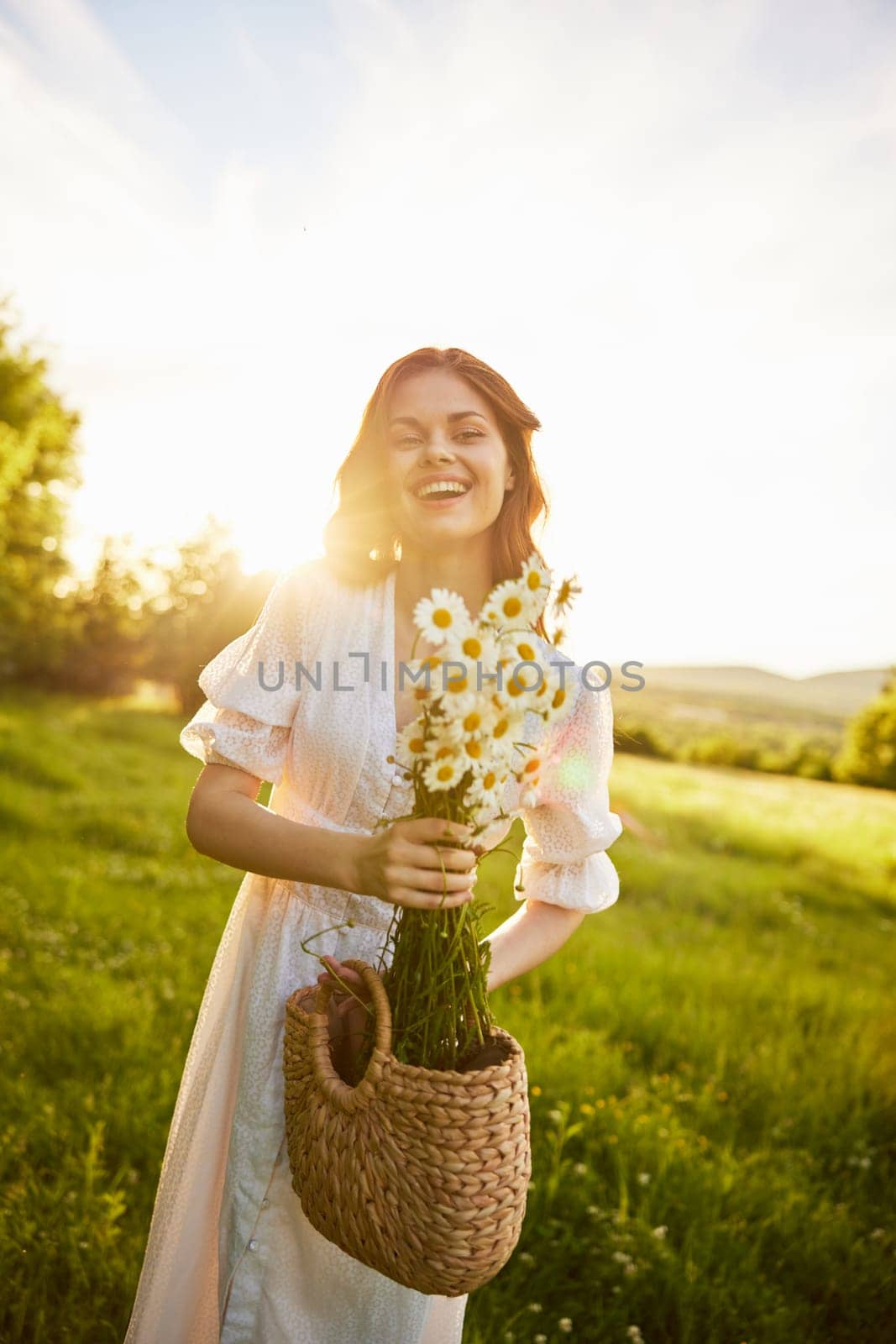 portrait of a woman in a light dress in a meadow with a bouquet of daisies and a wicker basket in her hands. High quality photo