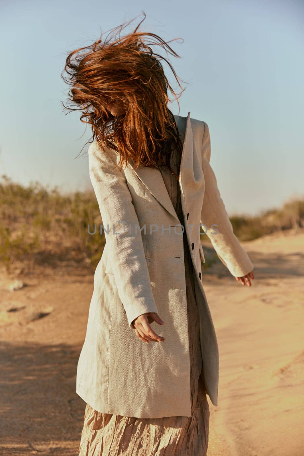 stylish woman with long red hair covering her face posing in nature. High quality photo