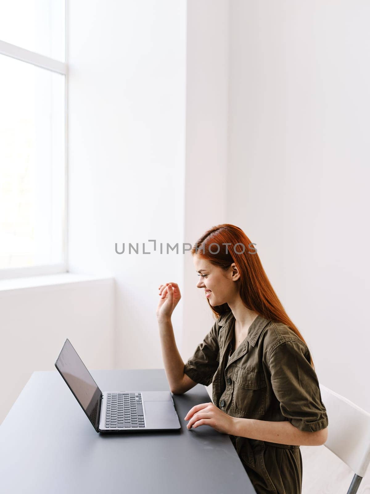 pensive woman sits in the office at the table with a laptop and works. High quality photo