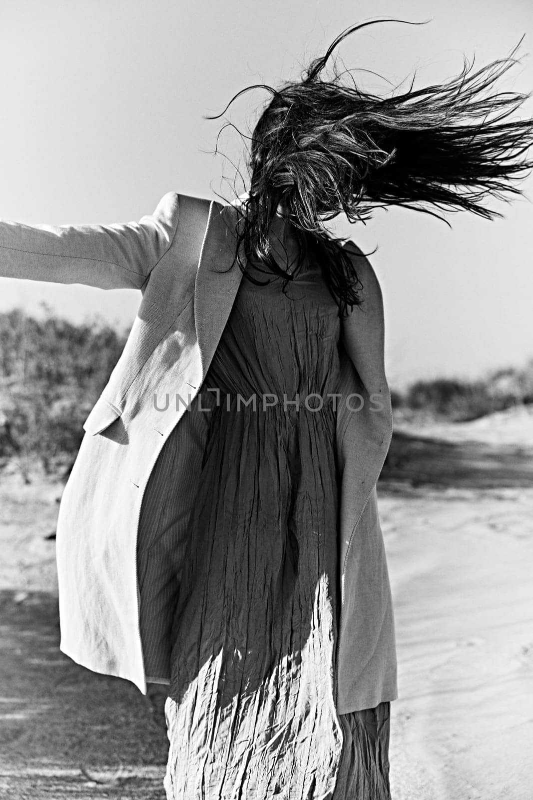 monochrome photo of a woman in a jacket against a clear sky on the coast. High quality photo