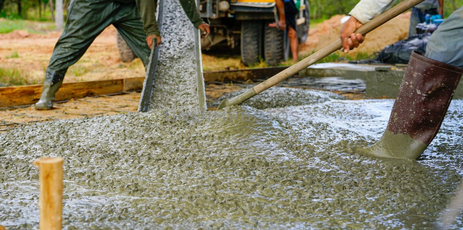 Construction worker pour wet concrete at construction site. Construction worker working with ready-mix concrete pouring from cement mixer truck. Construction contractor concept. Builder pour cement.                         