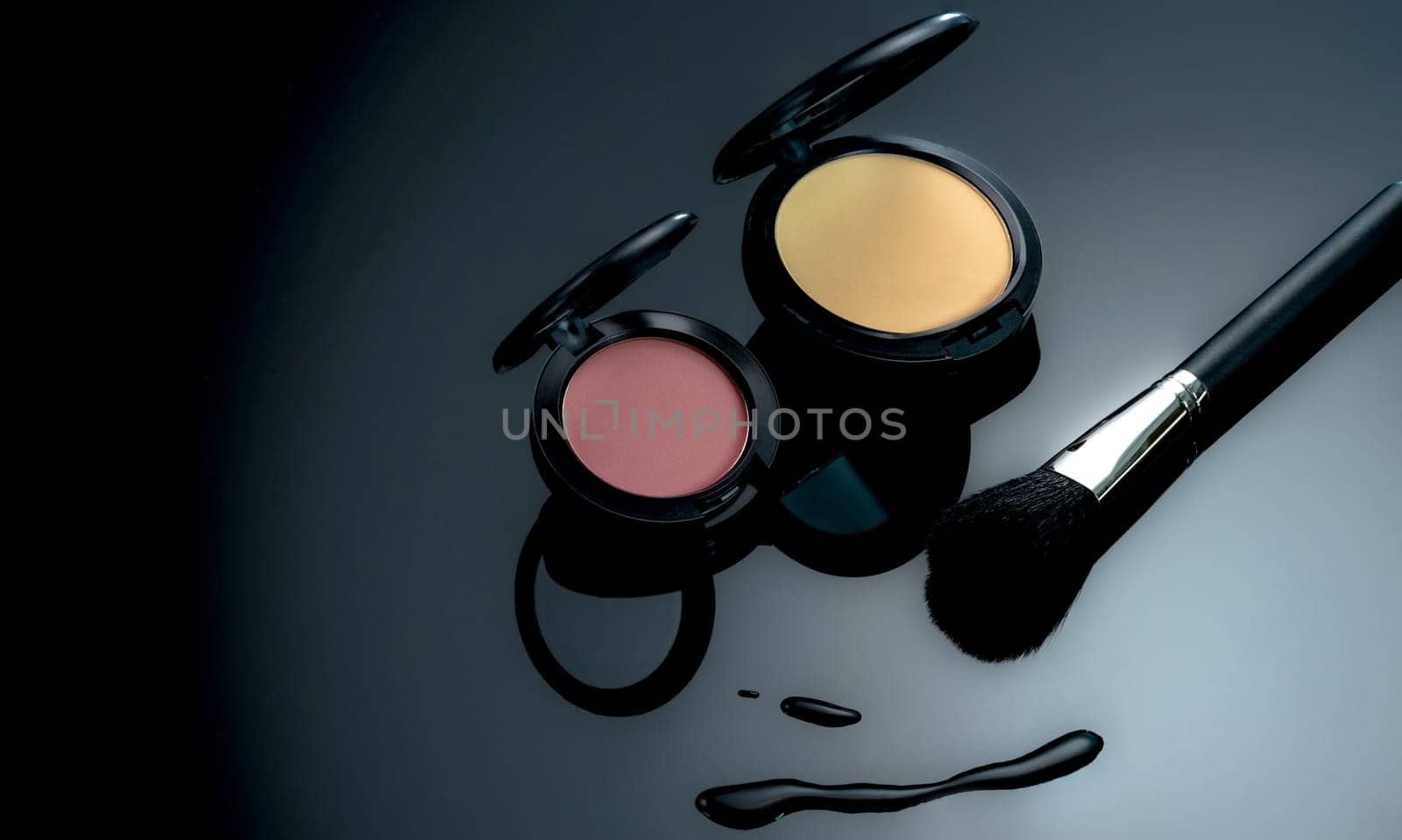 Powder blush, powder foundation, and makeup brush on black background. Cosmetic products. Makeup professionals cosmetics. Beauty fashion. Makeup professional powder foundation and pink powder blush.