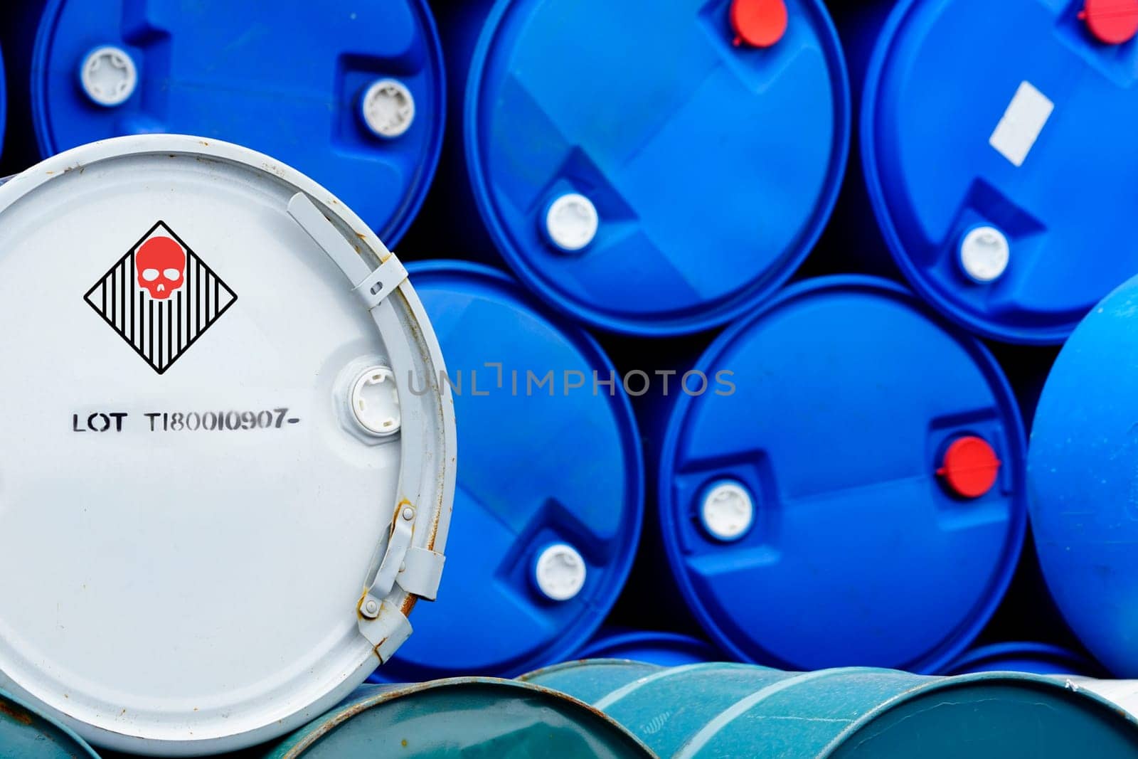 Old chemical barrels. Blue and green oil drum. Steel and plastic oil tank. Toxic waste warehouse. Hazard chemical barrel with warning label. Industrial waste in drum. Hazard waste storage in factory. by Fahroni