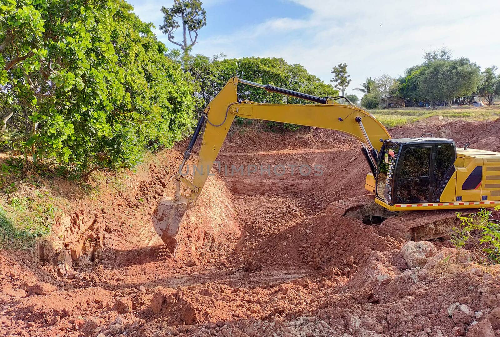 Backhoe bucket digging the soil at agriculture farm to make pond. Crawler excavator digging at shale layer. Excavating machine. Earth moving equipment. Excavation vehicle. Construction business. by Fahroni