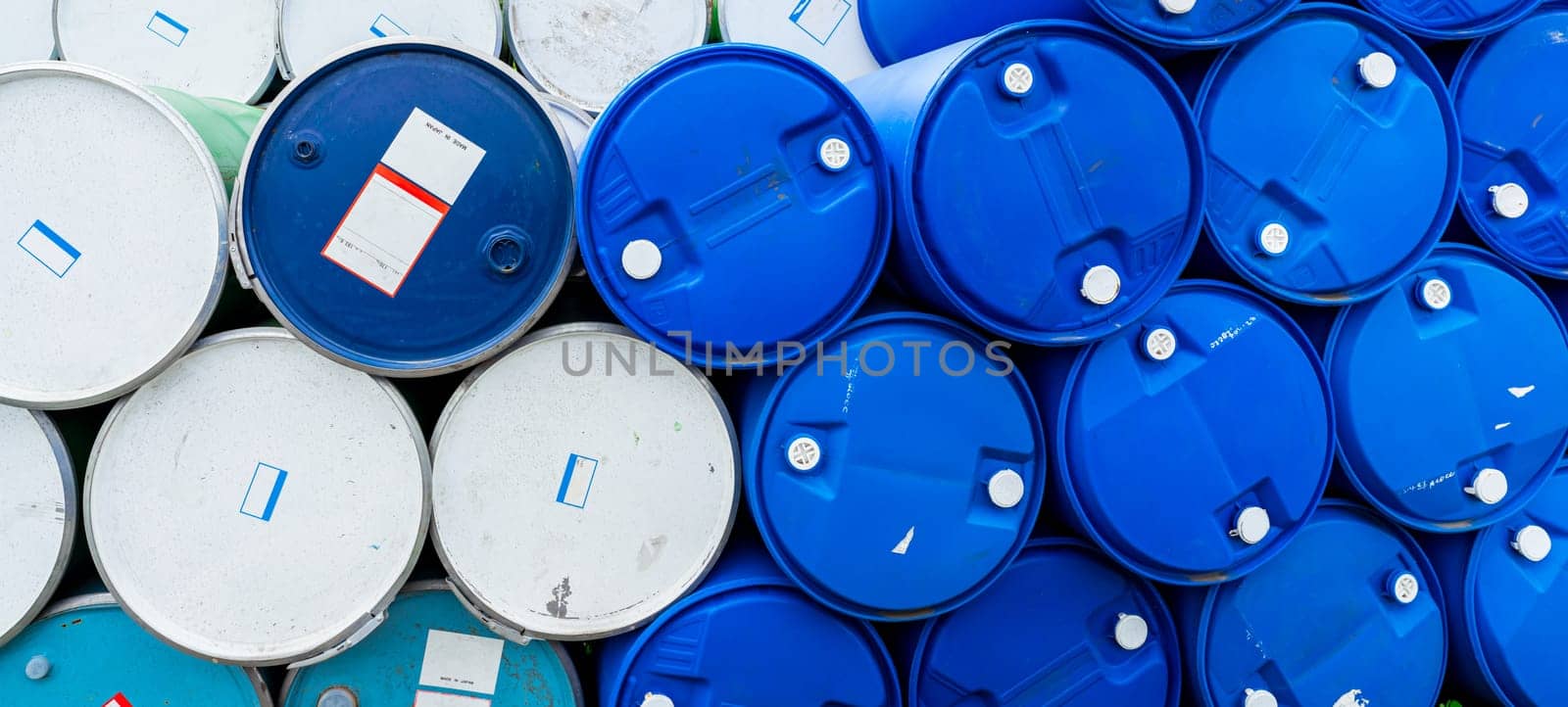 Old chemical barrels. Blue and green oil drum. Steel and plastic oil tank. Toxic waste warehouse. Hazard chemical barrel with warning label. Industrial waste in drum. Hazard waste storage in factory. 