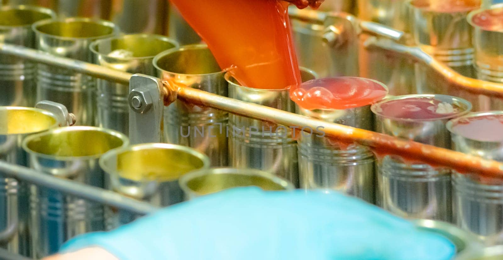 Canned fish factory. Food industry. Machine filling red tomato sauce into sardine can at food factory. Food processing production line. Food manufacturing industry. Cans of sardines on conveyor belt. by Fahroni