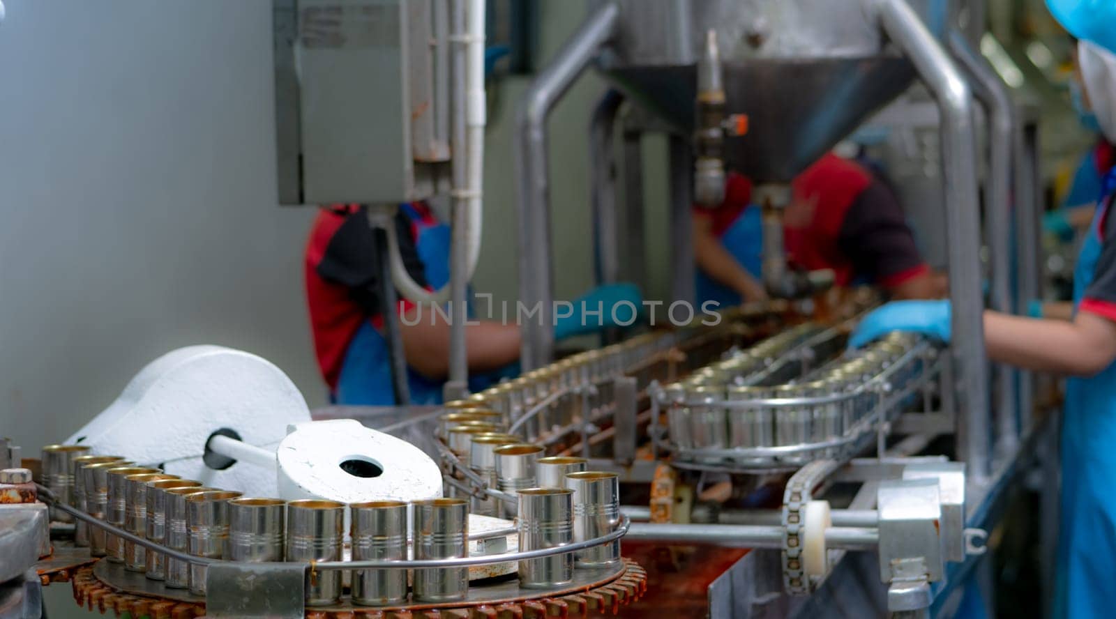 Canned fish factory. Food industry.  Sardines in red tomato sauce in tinned cans at food factory. Food processing production line. Food manufacturing industry. Many can of sardines on a conveyor belt. by Fahroni