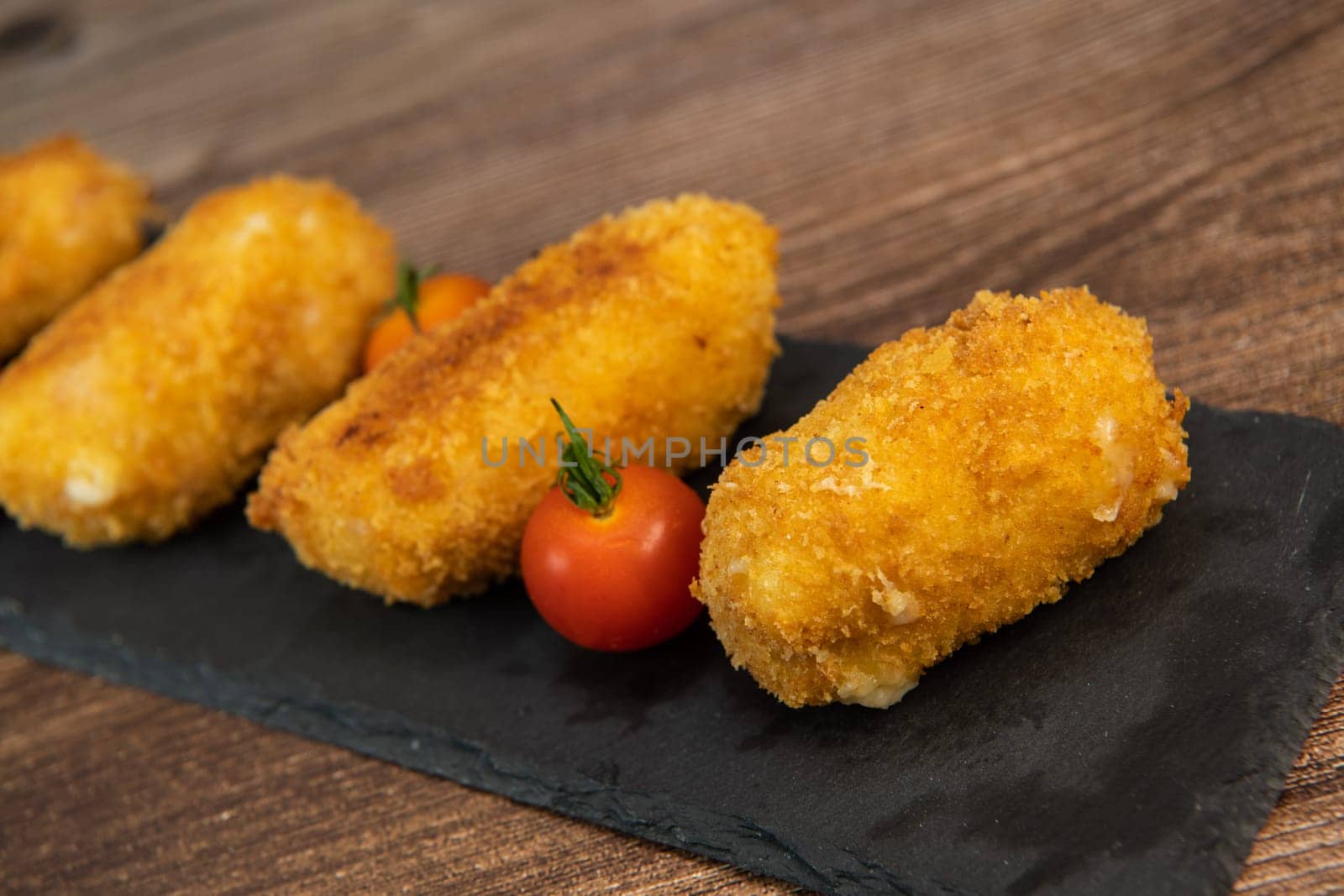 Homemade traditional Spanish croquettes or croquetas on a black plate with fork, Tapas food, High quality photo