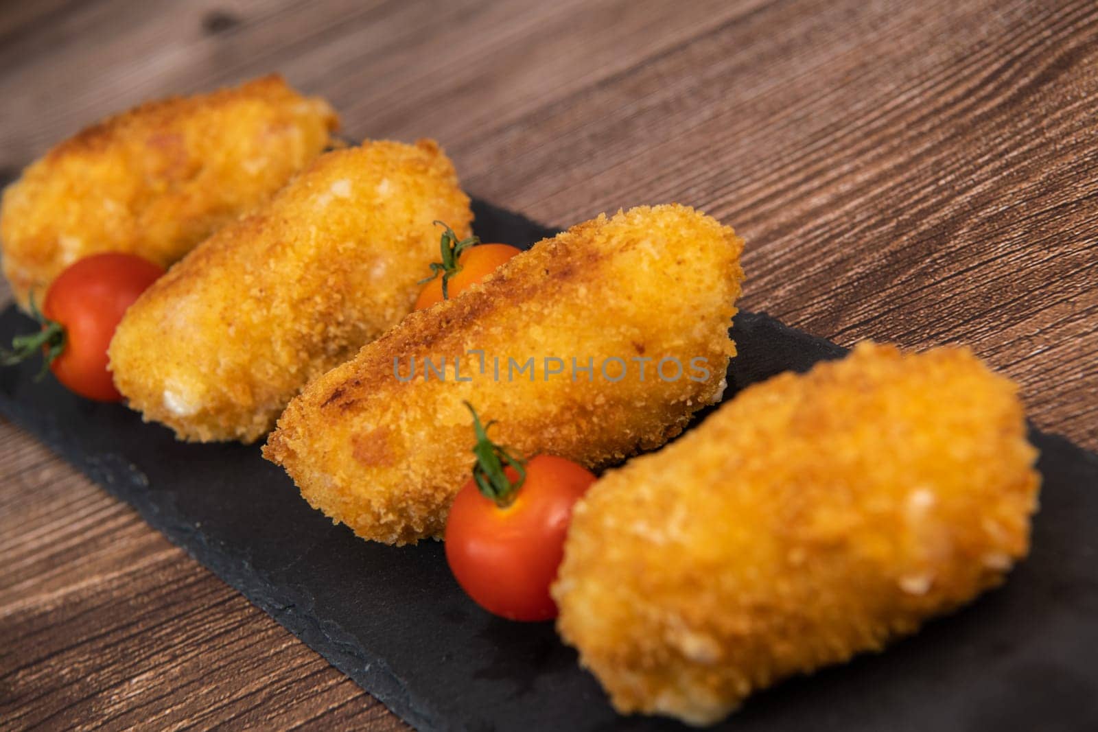 Homemade traditional Spanish croquettes or croquetas on a black plate with fork, Tapas food, High quality photo
