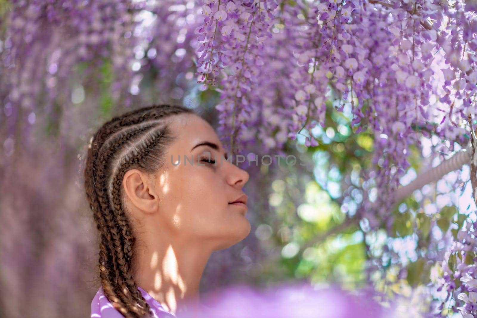 Woman wisteria lilac dress. Thoughtful happy mature woman in purple dress surrounded by chinese wisteria.