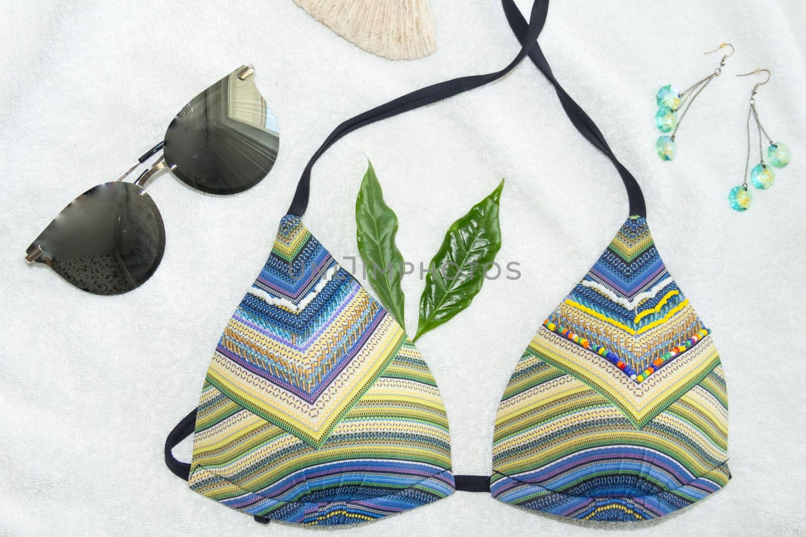 A bikini swimsuit, rhinestone earrings and sunglasses on a white towel. by Alla_Yurtayeva