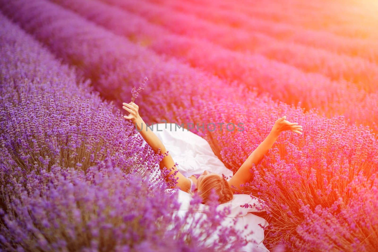 A middle-aged woman lies in a lavender field and enjoys aromatherapy. Aromatherapy concept, lavender oil, photo session in lavender.