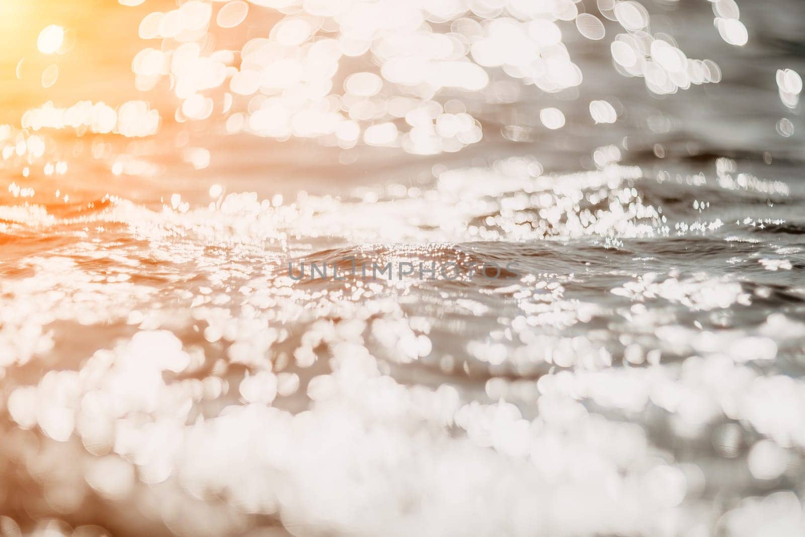 Abstract sea summer ocean sunset nature background. Sound of small waves on golden water surface in motion blur with golden bokeh lights from sun. Holiday, vacation and recreational concept.
