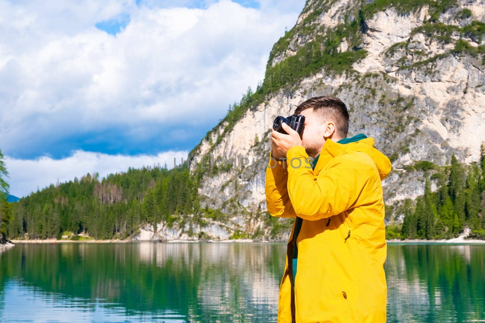 Young man photographer holding a camera and taking photos of the Alps.