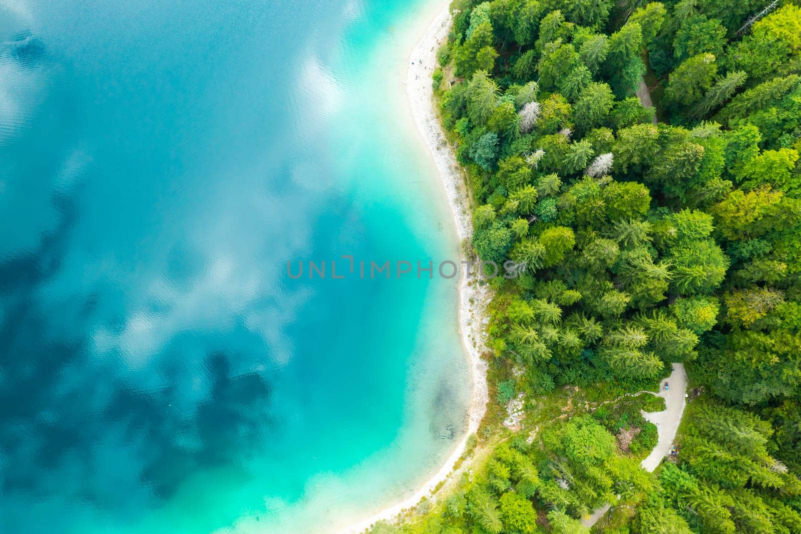 Aerial view of a lake with turquoise water and clouds reflection and pine trees on the shore by vladimka