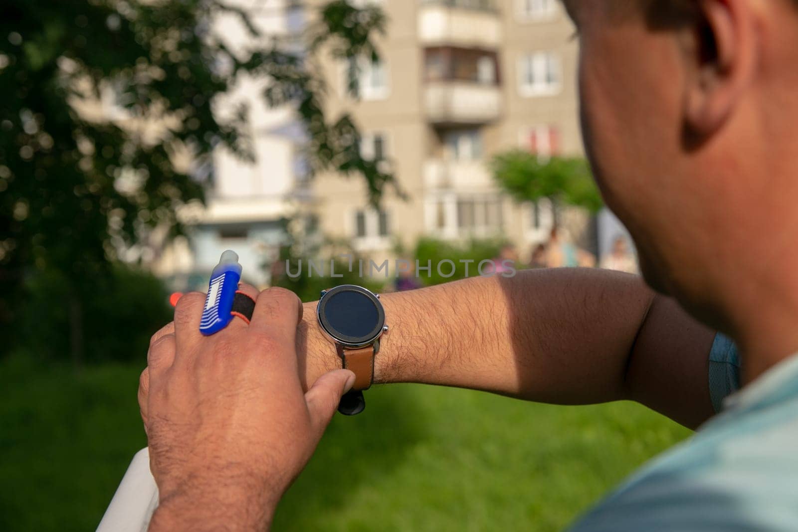 An athlete participating in orienteering competitions sets up a smartwatch before the start. by BY-_-BY