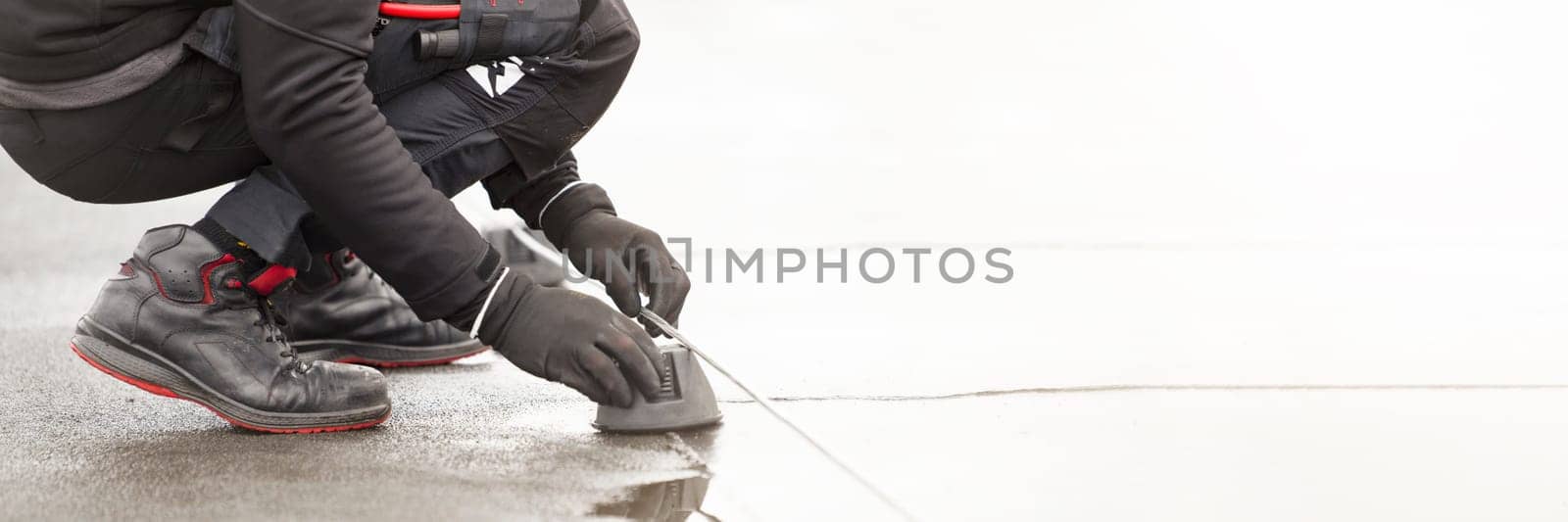 Ground wire. A worker lays a ground cable on the roof of a building. Electrician fixing aluminum wire for grounding solar panels.